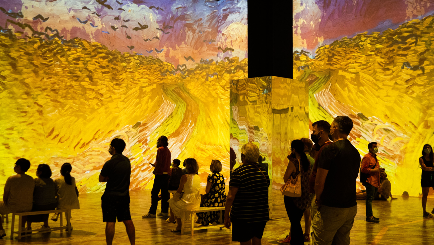 Socially distanced groups stand amidst an immersive Van Gogh experience